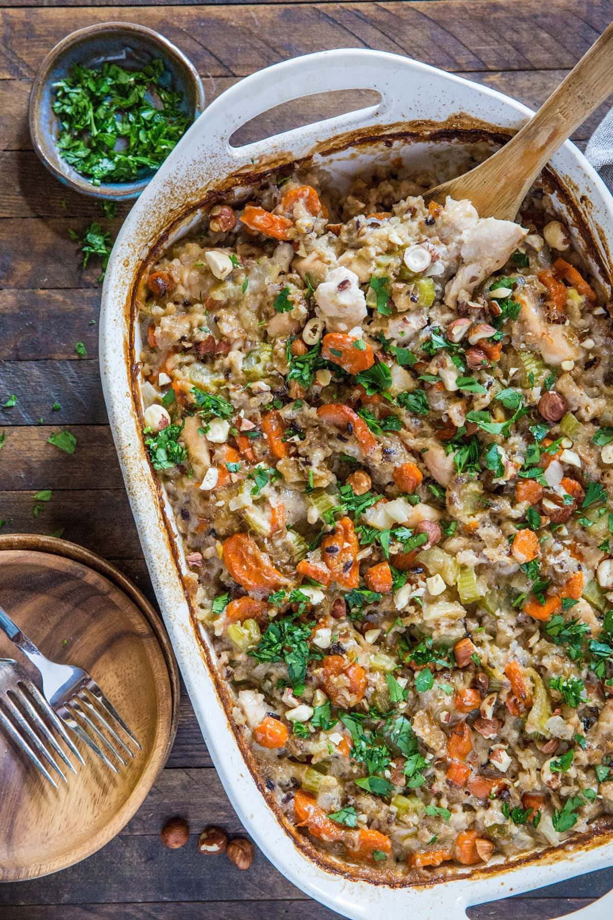 casserole dish of wild rice chicken casserole on rustic backdrop with two plates to the side