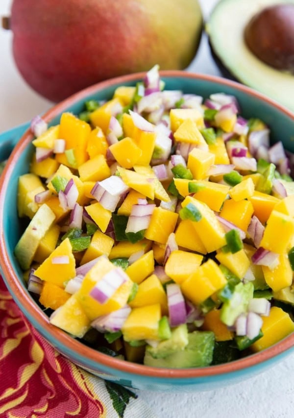 Blue bowl of mango avocado salsa, ready to be enjoyed on top of fish tacos or chicken breasts.