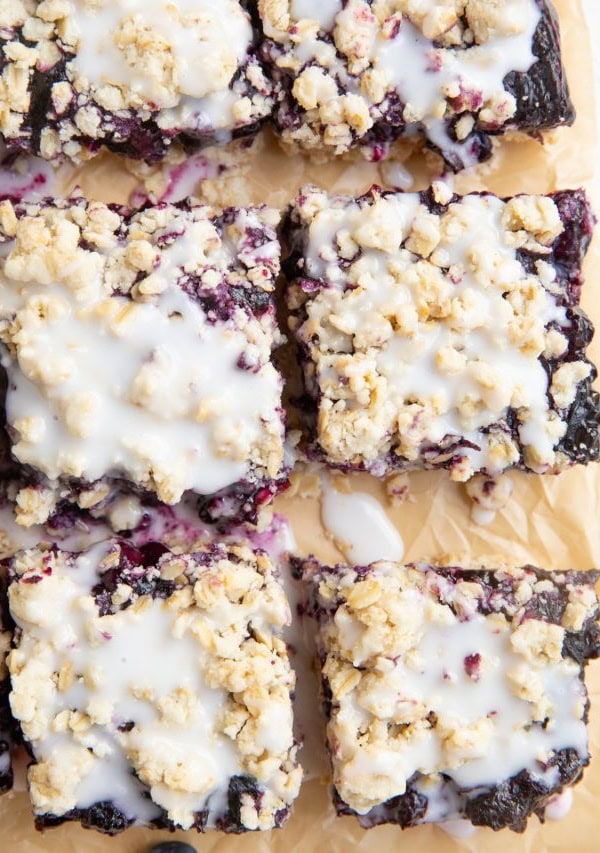 Blueberry crumb bars cut on a piece of parchment paper.