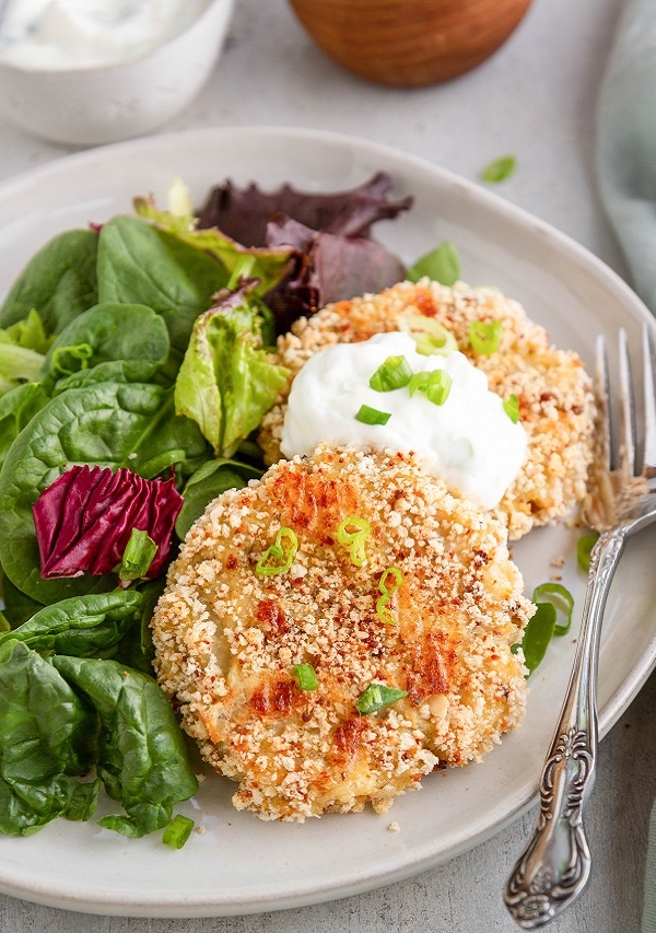 Potato cakes on a white plate with a side salad.