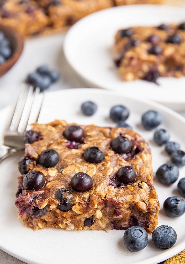 Two blueberry bars on two white plates.