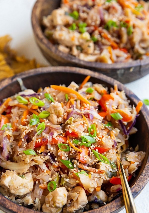 Two wooden bowls of teriyaki chicken and cabbage