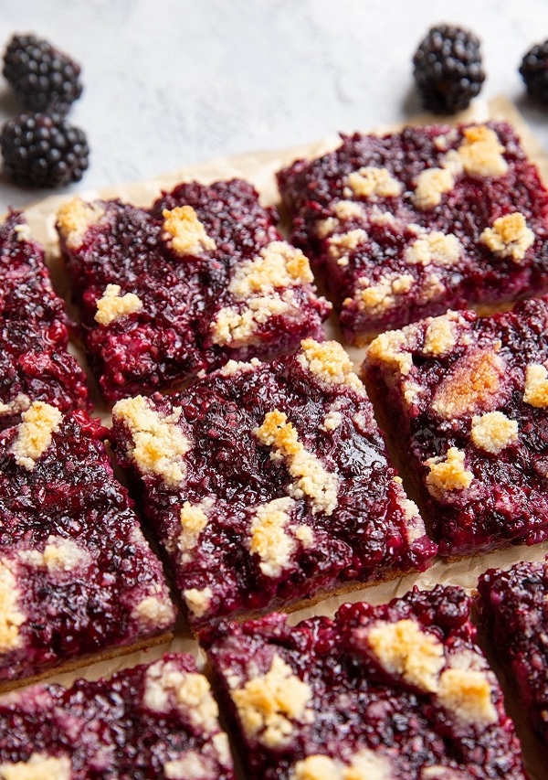 Blackberry crumb bars cut into squares on a sheet of parchment paper