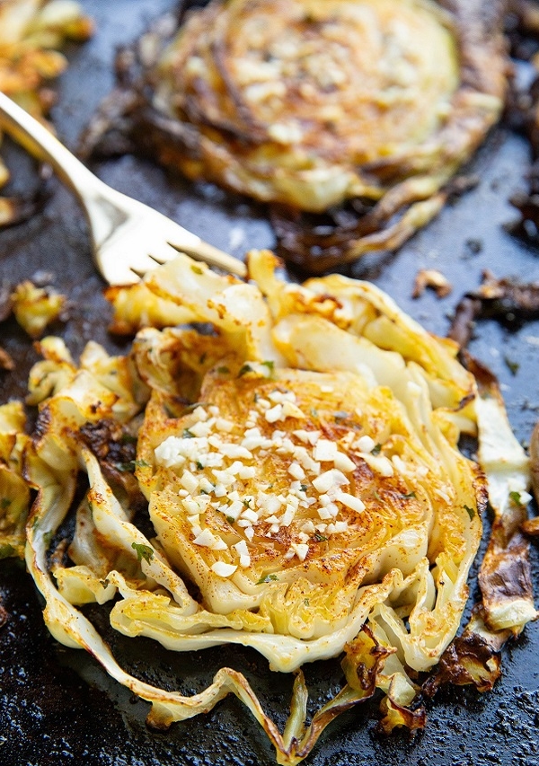 baking sheet with roasted cabbage with a fork taking a bite