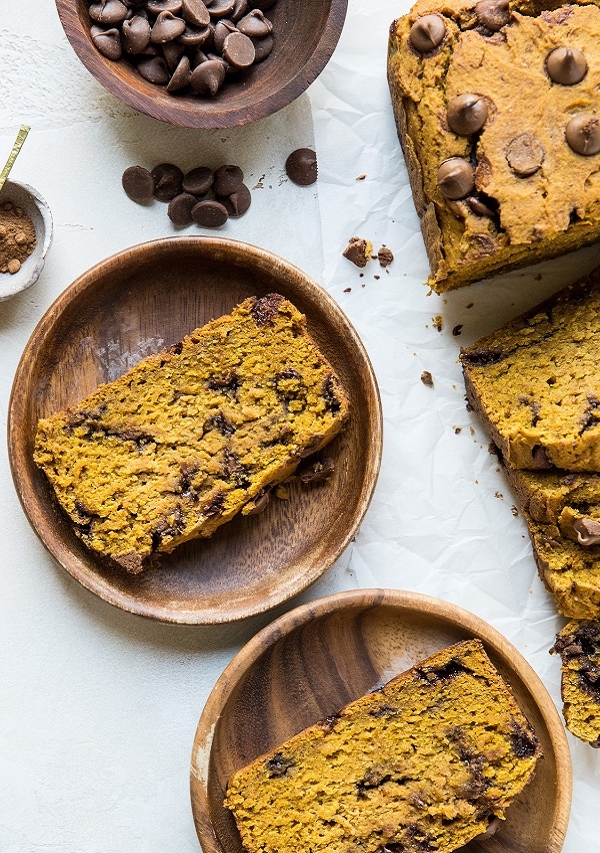 Loaf of gluten-free pumpkin bread with slices of pumpkin bread on wooden plates.