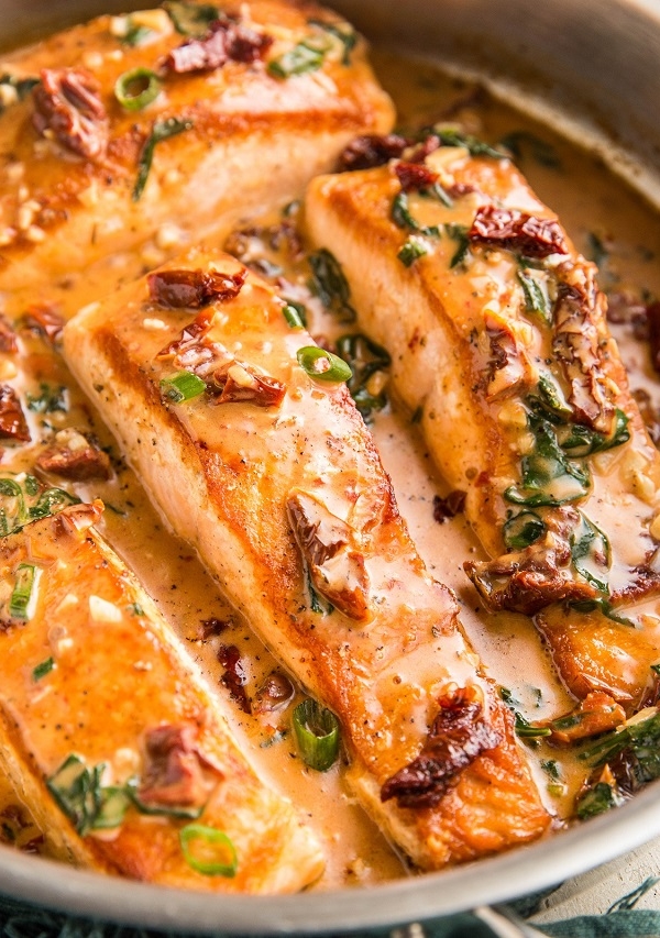 Skillet with sun-dried tomato salmon in a creamy sauce.