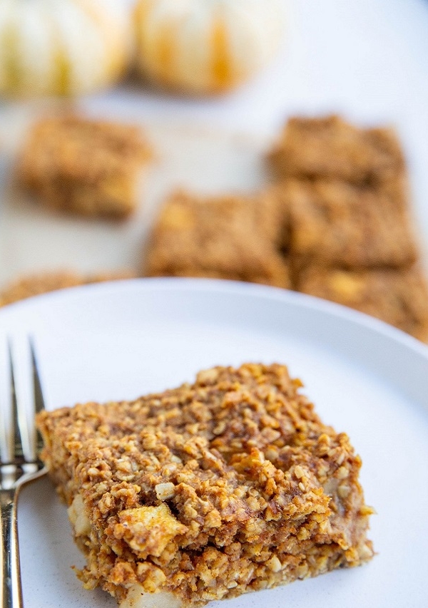 Big pumpkin apple bar on a plate with a fork with more bars in the background.