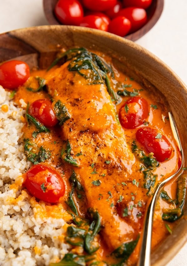 Salmon in a wood bowl with creamy roasted red pepper sauce.