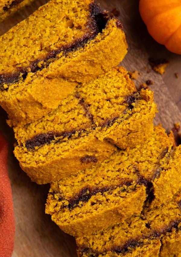 Loaf of cinnamon swirl pumpkin oatmeal bread on a wooden cutting board.