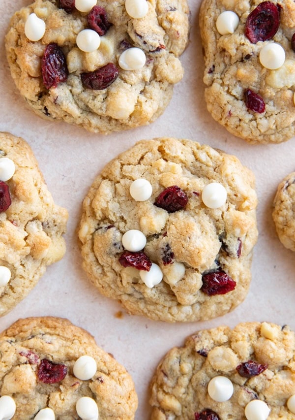 Cranberry white chocolate macadamia nut cookies on a pink background.