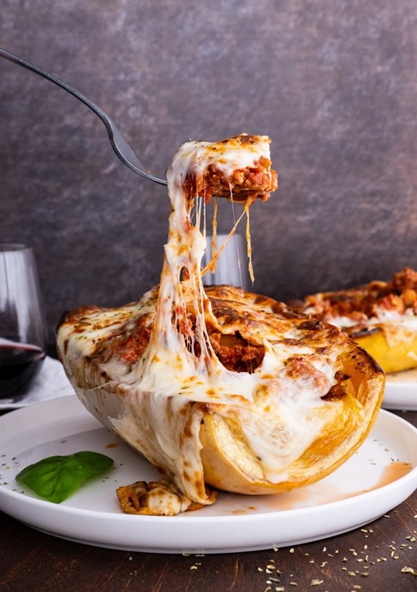 Spaghetti squash lasagna boat with a fork doing a cheese pull off of the squash.