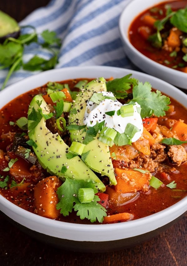 Bowls of ground turkey chili made paleo friendly with sliced avocado on top.