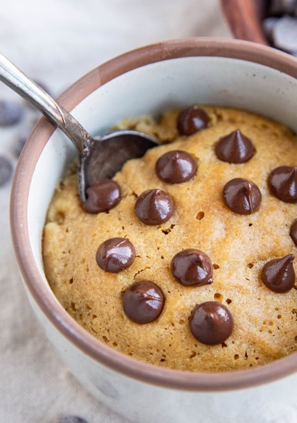 Close up image of a peanut butter cookie in a mug with chocolate chips