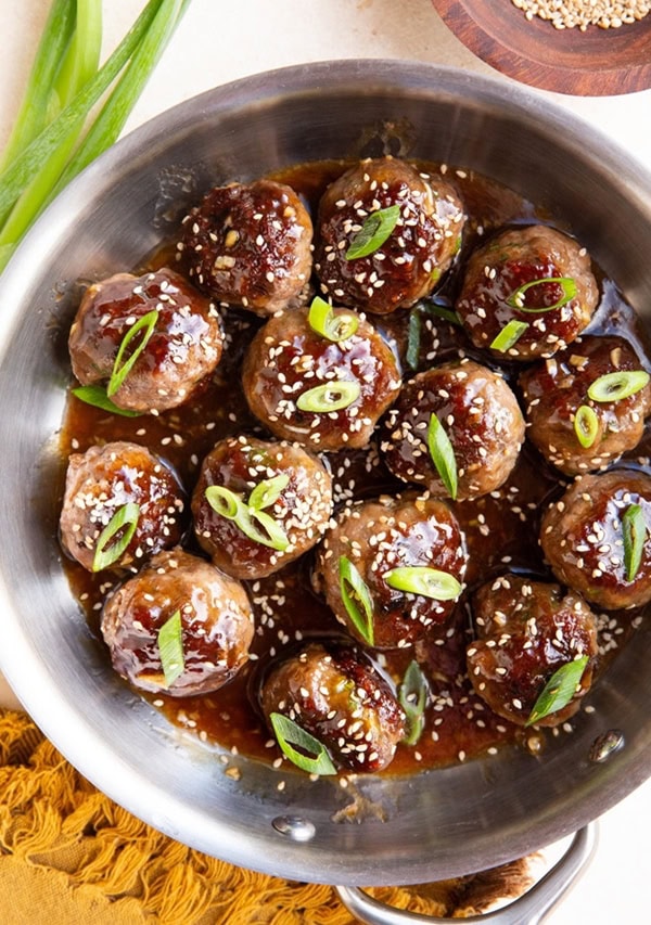 Stainless steel skillet of glazed meatballs.