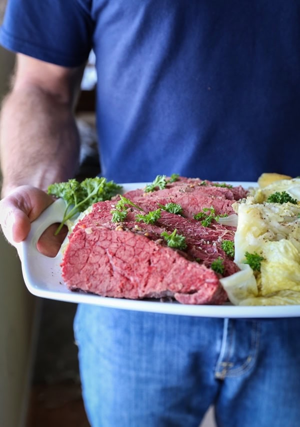 Man holding a platter of corned beef and cabbage