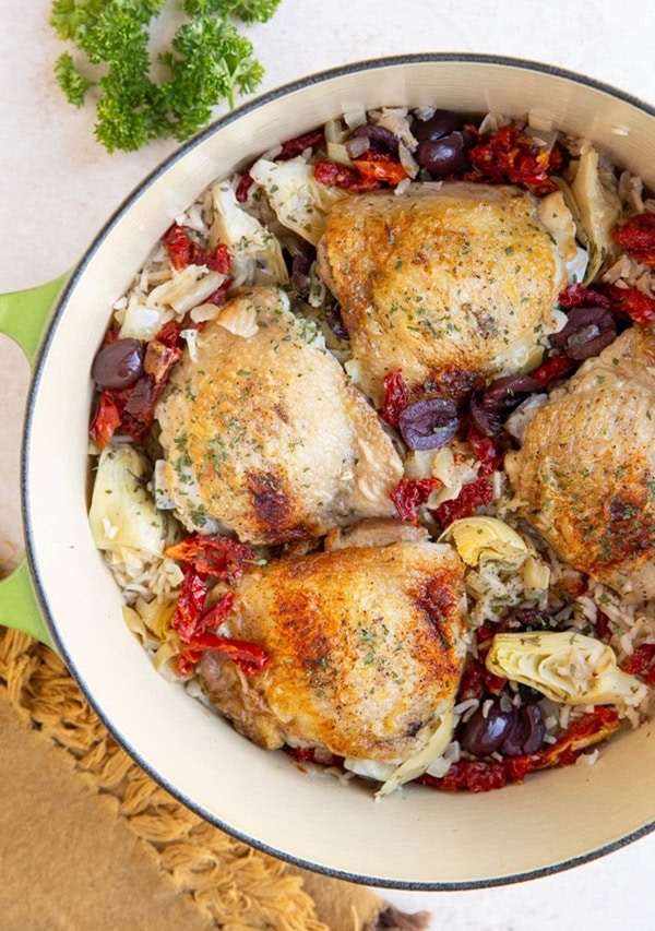 Pot of Mediterranean chicken with rice and sun-dried tomatoes, kalamata olives, and artichoke hearts.