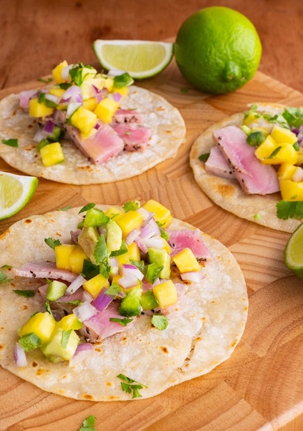 Seared Ahi Tacos on a wooden cutting board with mango salsa.