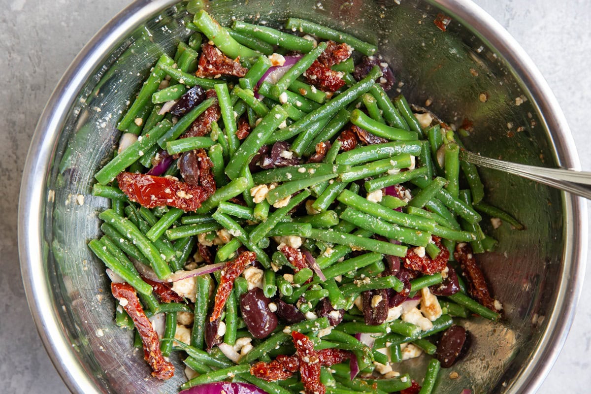 Green bean salad freshly tossed in a mixing bowl.