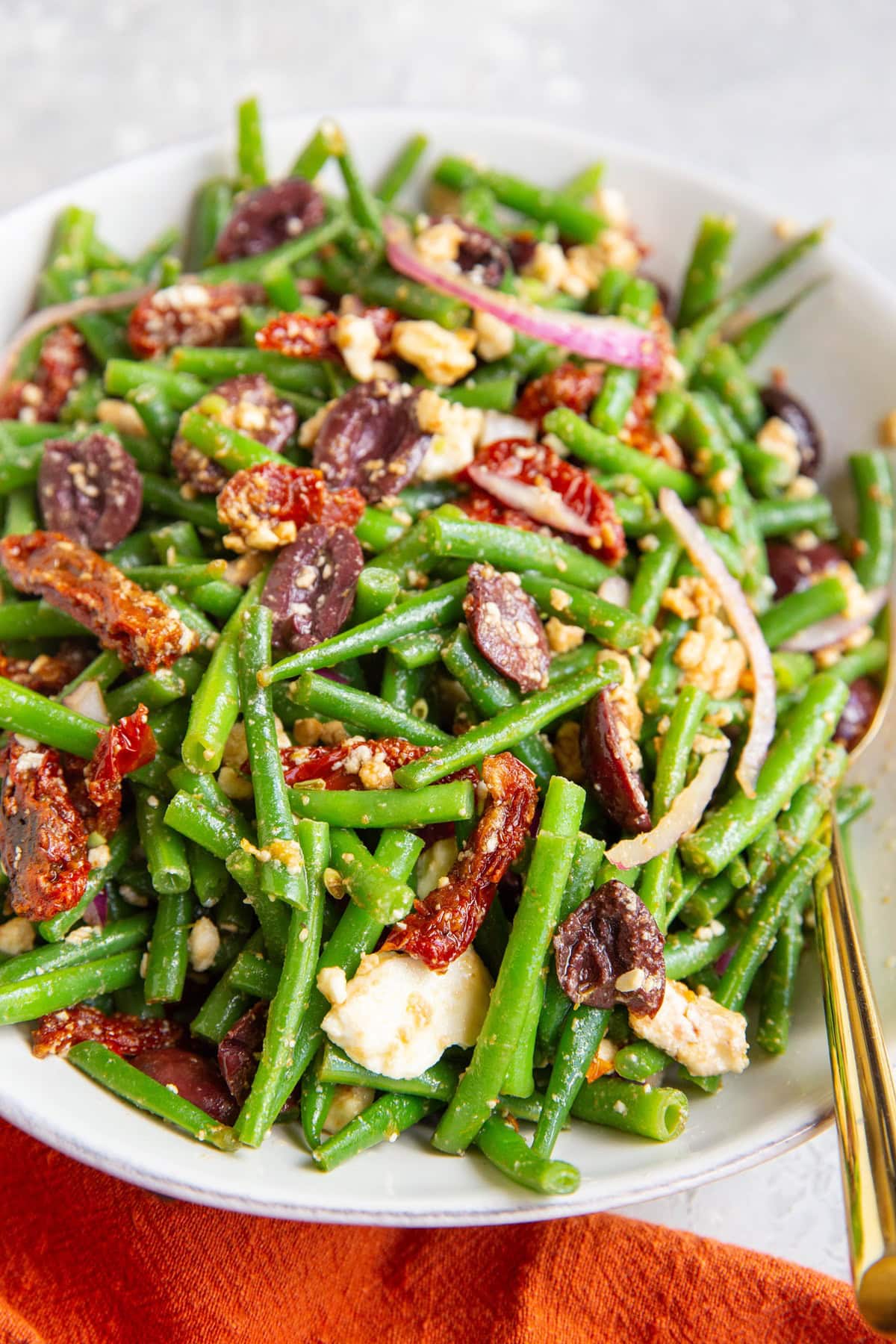 Green bean salad in a large serving bowl with a spoon to the side, ready to serve it up.