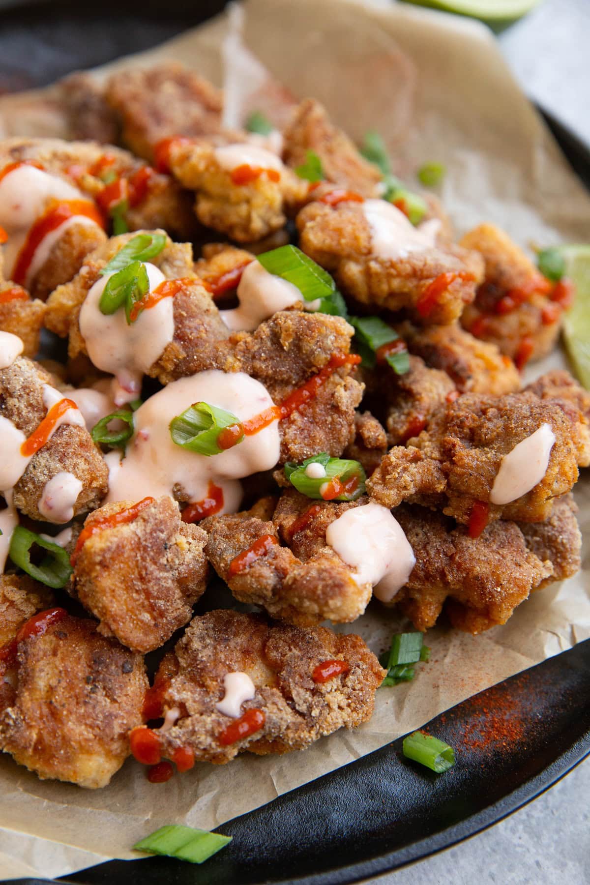 Plate full of crispy chicken nuggets, drizzled in sauces.