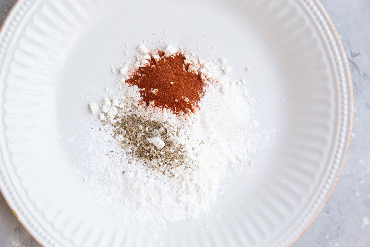 Plate with flours and seasonings on top to bread chicken.