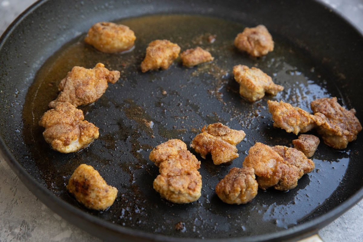 Chicken nuggets cooking in a skillet to golden brown perfection.