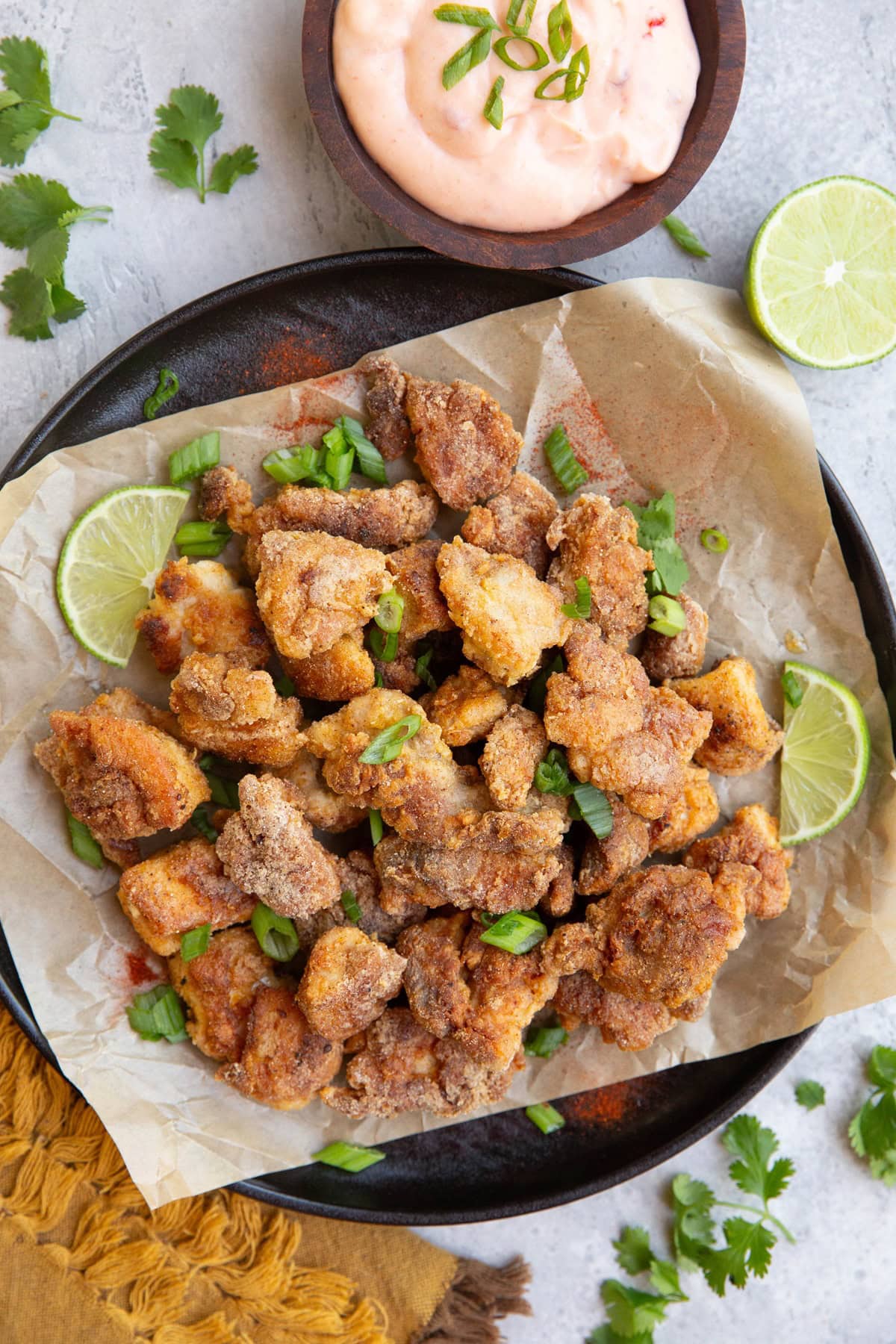 Plate of bang bang chicken with a bowl of bang bang sauce to the side, fresh cilantro sprinkled around.