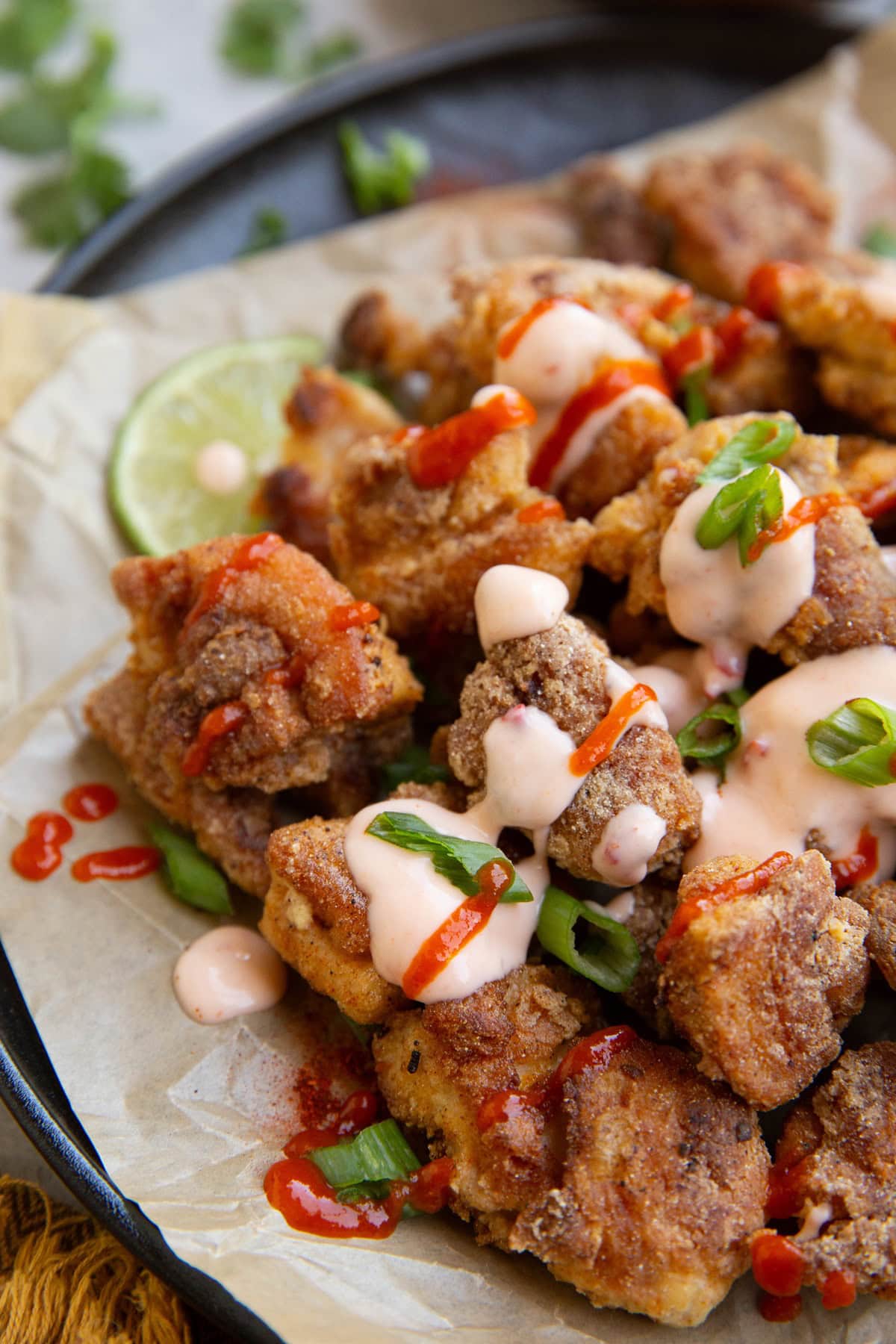 Plate of crispy bang bang chicken bites drizzled with bang bang sauce.