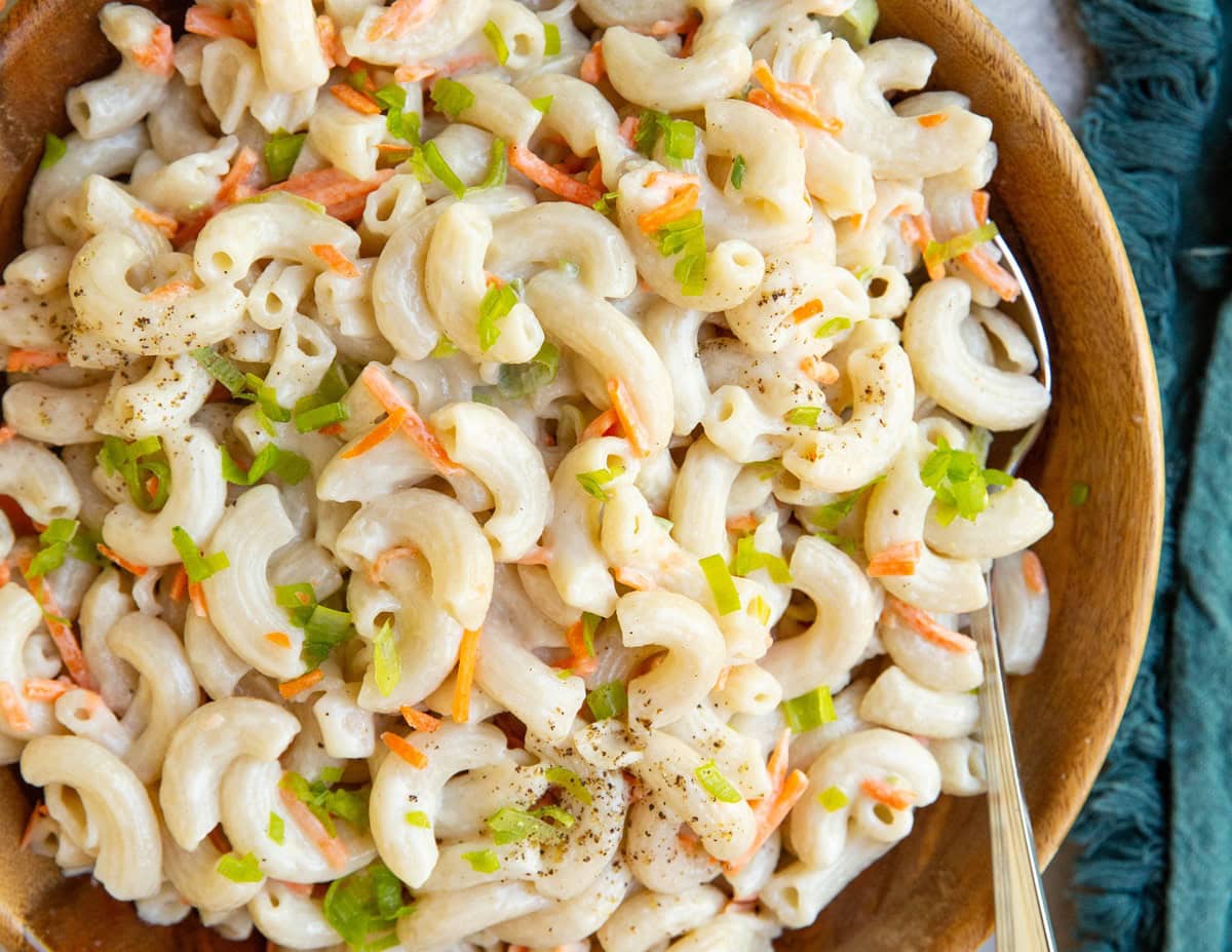 Wooden bowl of macaroni salad with a blue napkin to the side.