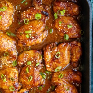 Baking dish full of chicken thighs sitting in marinade, fresh out of the oven.