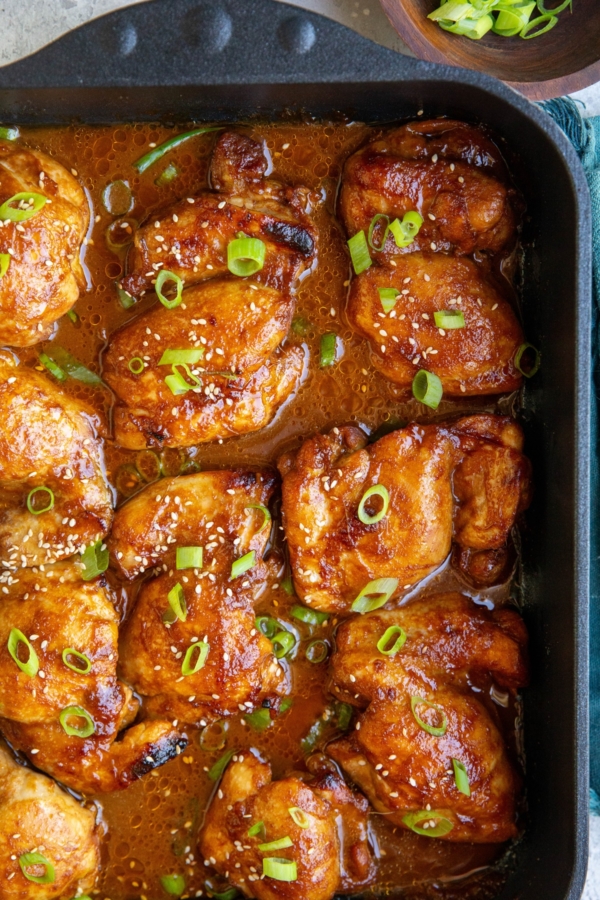 Baking dish full of chicken thighs sitting in marinade, fresh out of the oven.