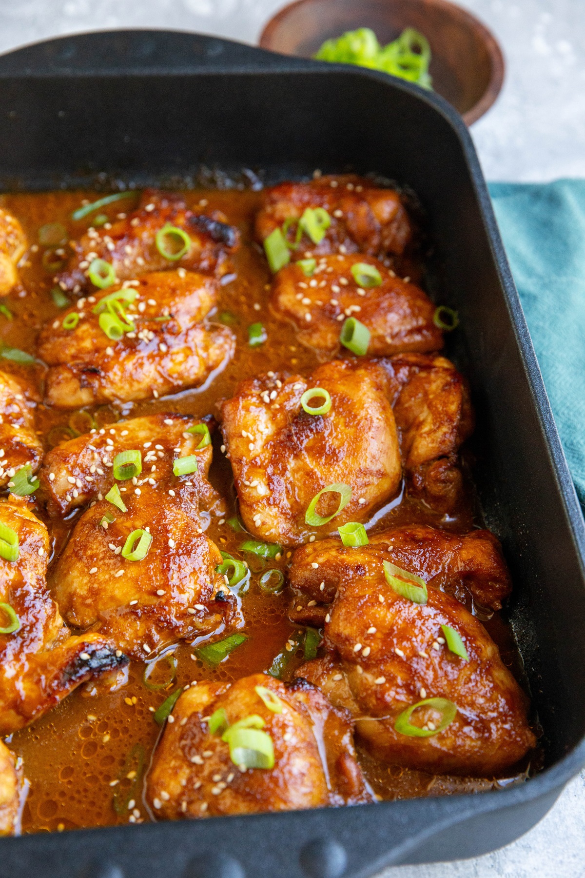 Baking dish with baked chicken thighs inside, drenched in marinade.