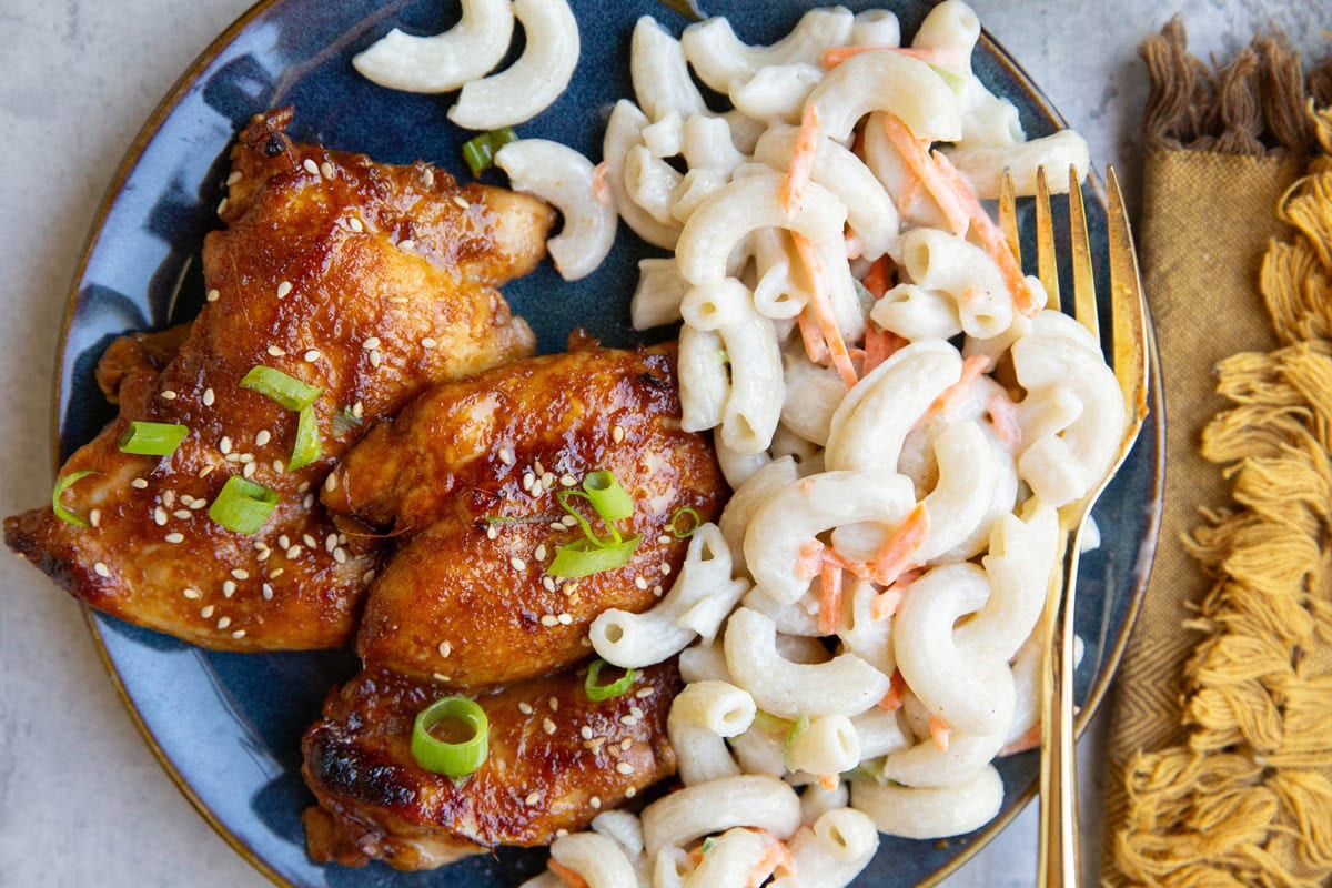 Blue plate of chicken with macaroni salad.