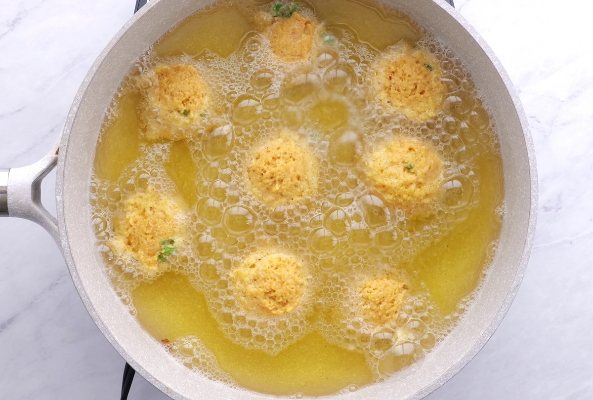 Hush puppies in a pot of oil being deep fried.