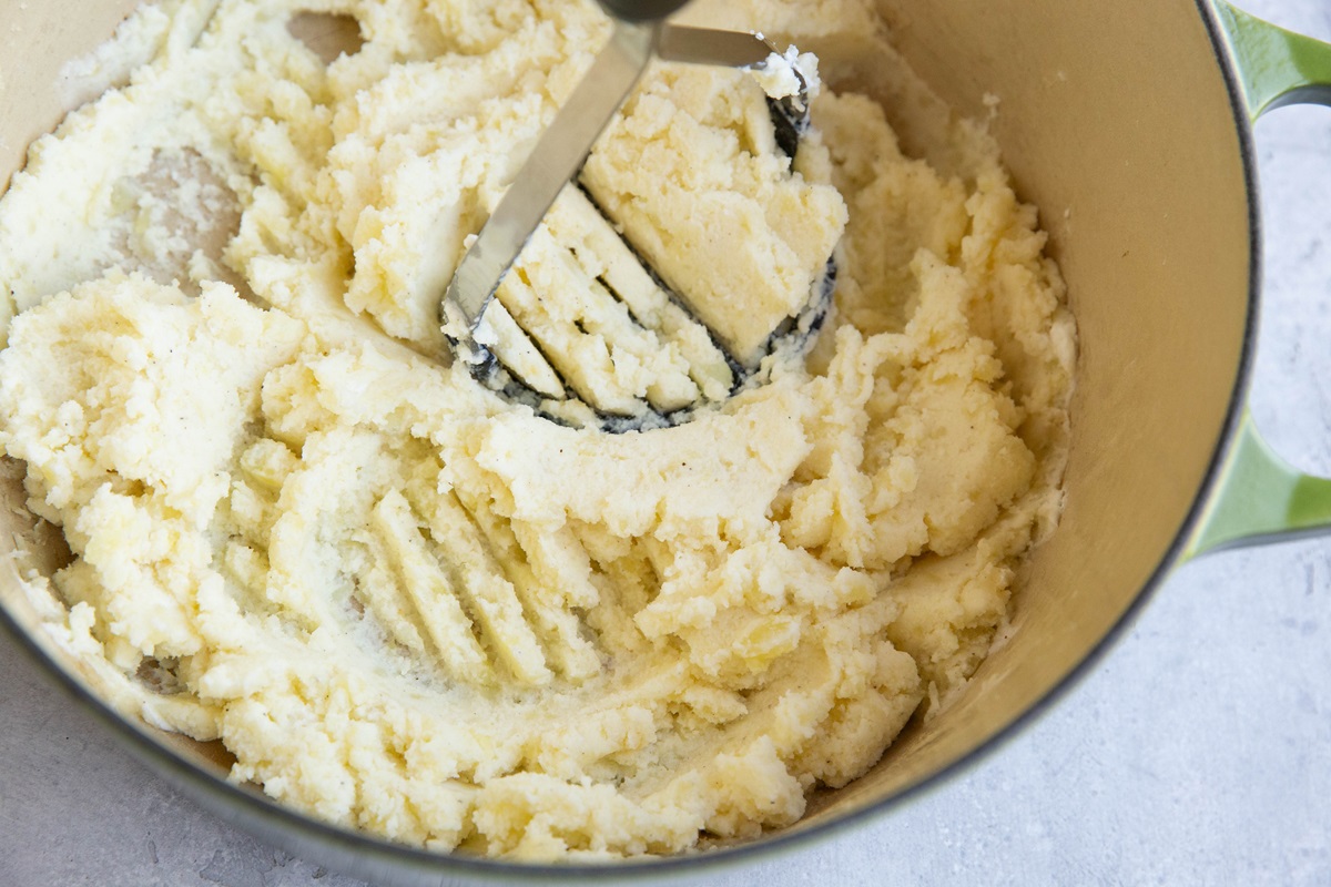 Mashing potatoes with a potato masher.