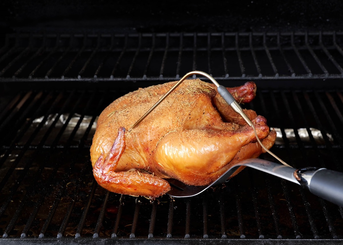 Smoked chicken being pulled out of a smoker.