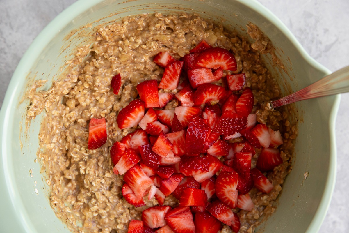 Fresh chopped strawberries on top of the oatmeal mixture, ready to be mixed in.