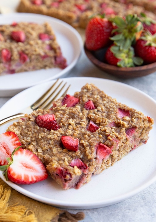 Two white plates with strawberry breakfast bars, ready to eat.