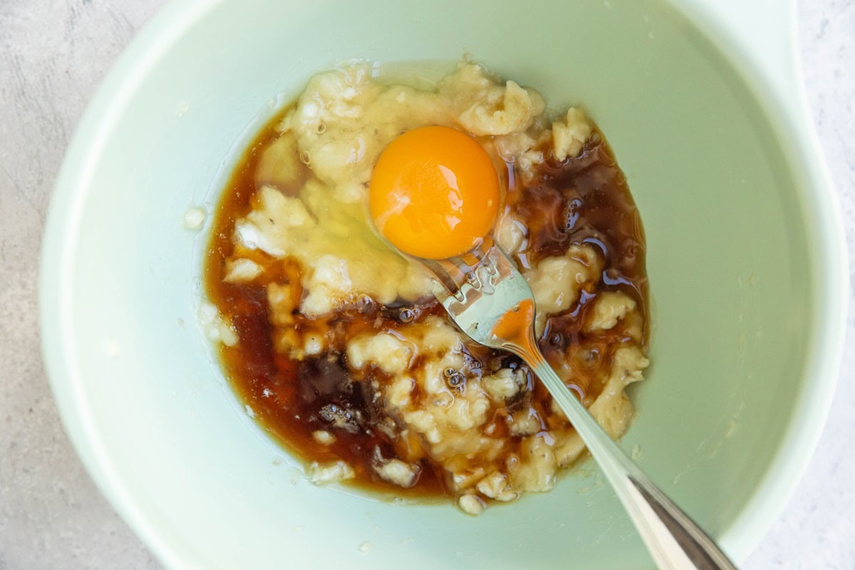 Mashed banana, egg, and pure maple syrup in a mixing bowl to make banana cookies.