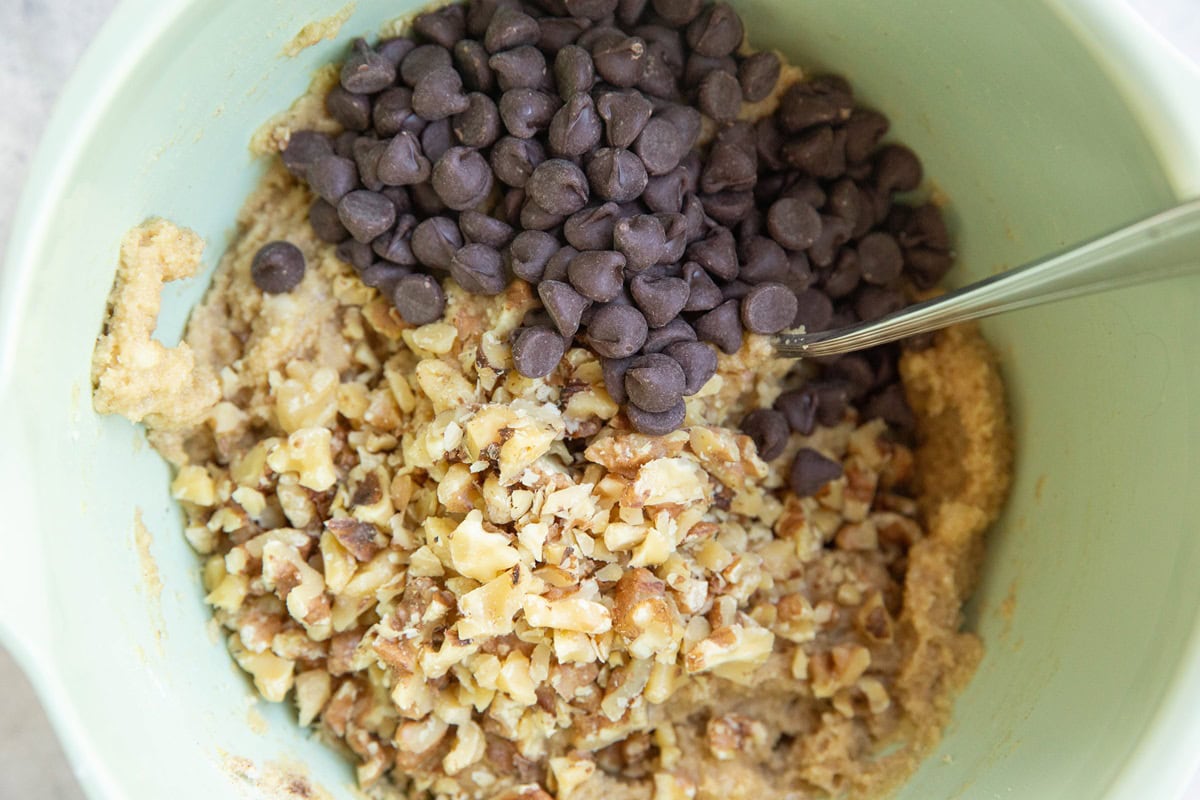 Mixing bowl with cookie dough, chocolate chips and walnuts.