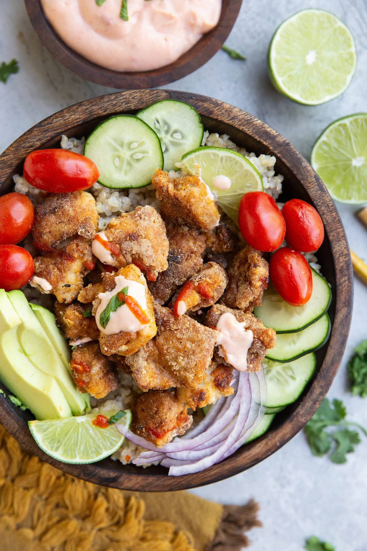 Wooden bowl of crispy chicken, rice, and vegetables.