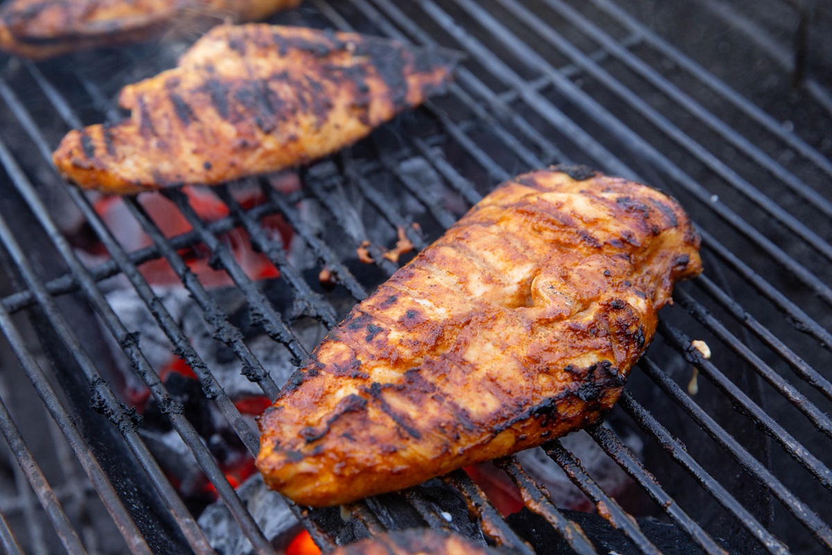 Grilled chicken on a grill with coals underneath.