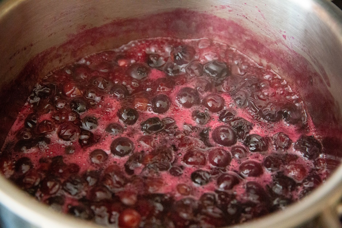 Blueberries stewing in a saucepan to make blueberry topping.