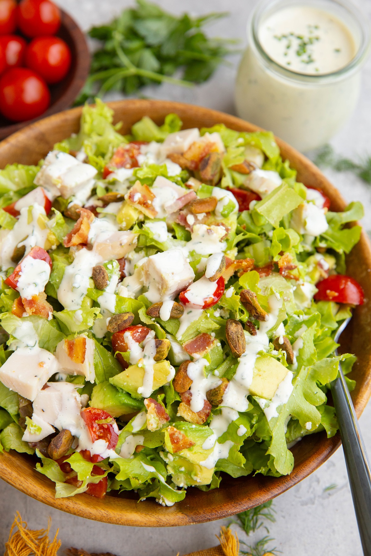 Big wooden bowl of salad drizzled with creamy homemade ranch dressing.