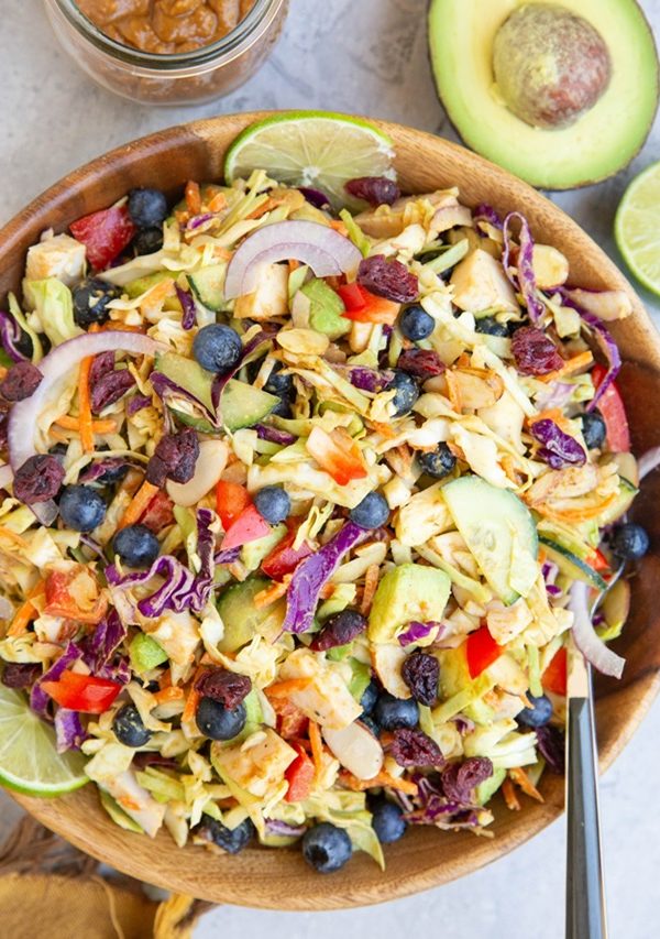 Cabbage salad in a wooden bowl with fresh veggies and peanut dressing.