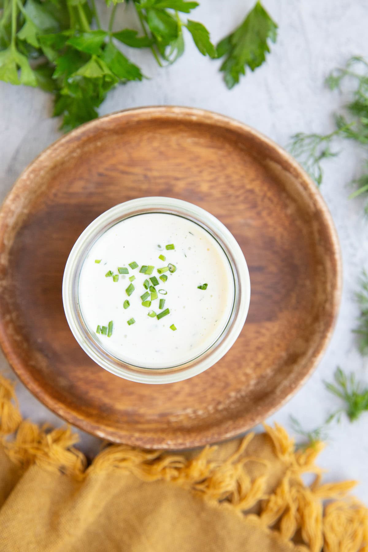 Dressing in a jar with a napkin and fresh herbs to the side.