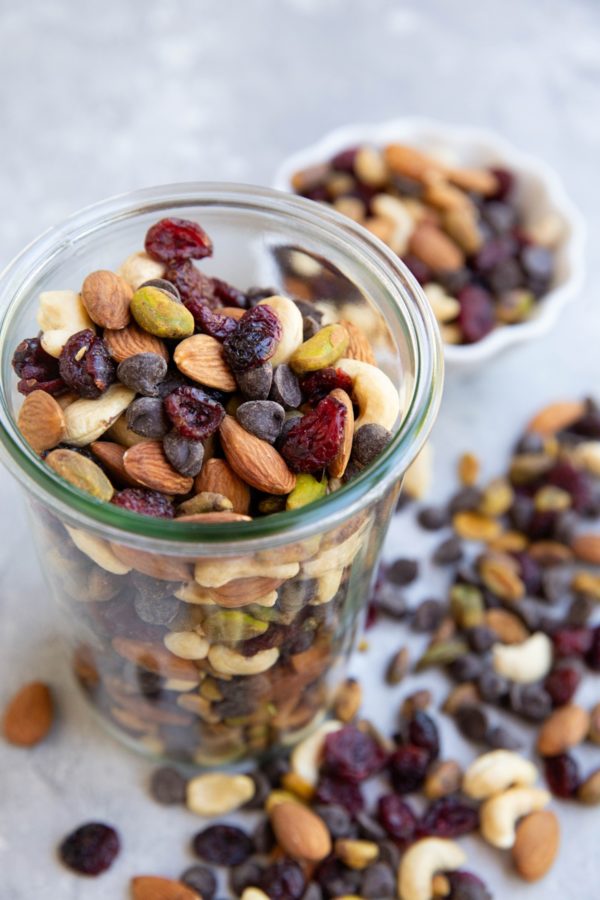 Glass jar of trail mix with trail mix scattered about.