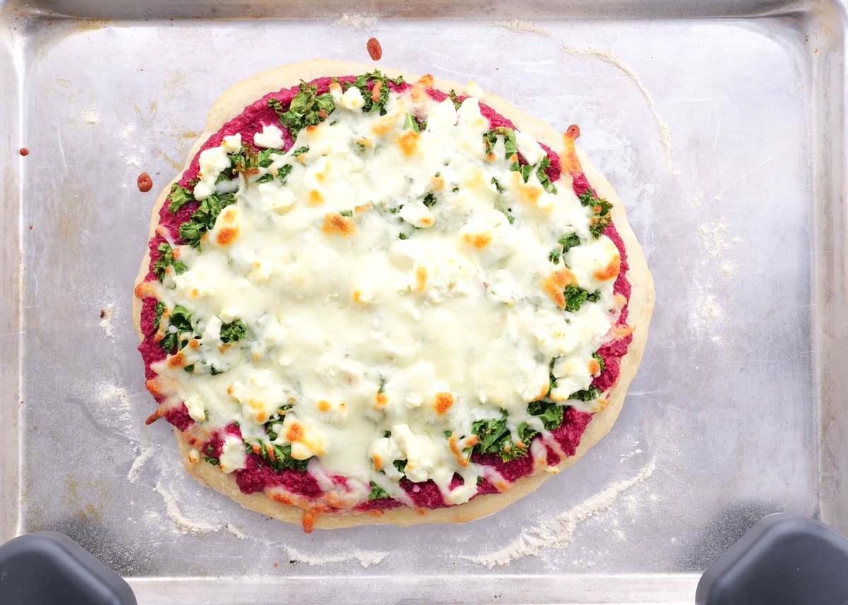 Homemade pizza fresh out of the oven with beet pesto, kale and goat cheese.