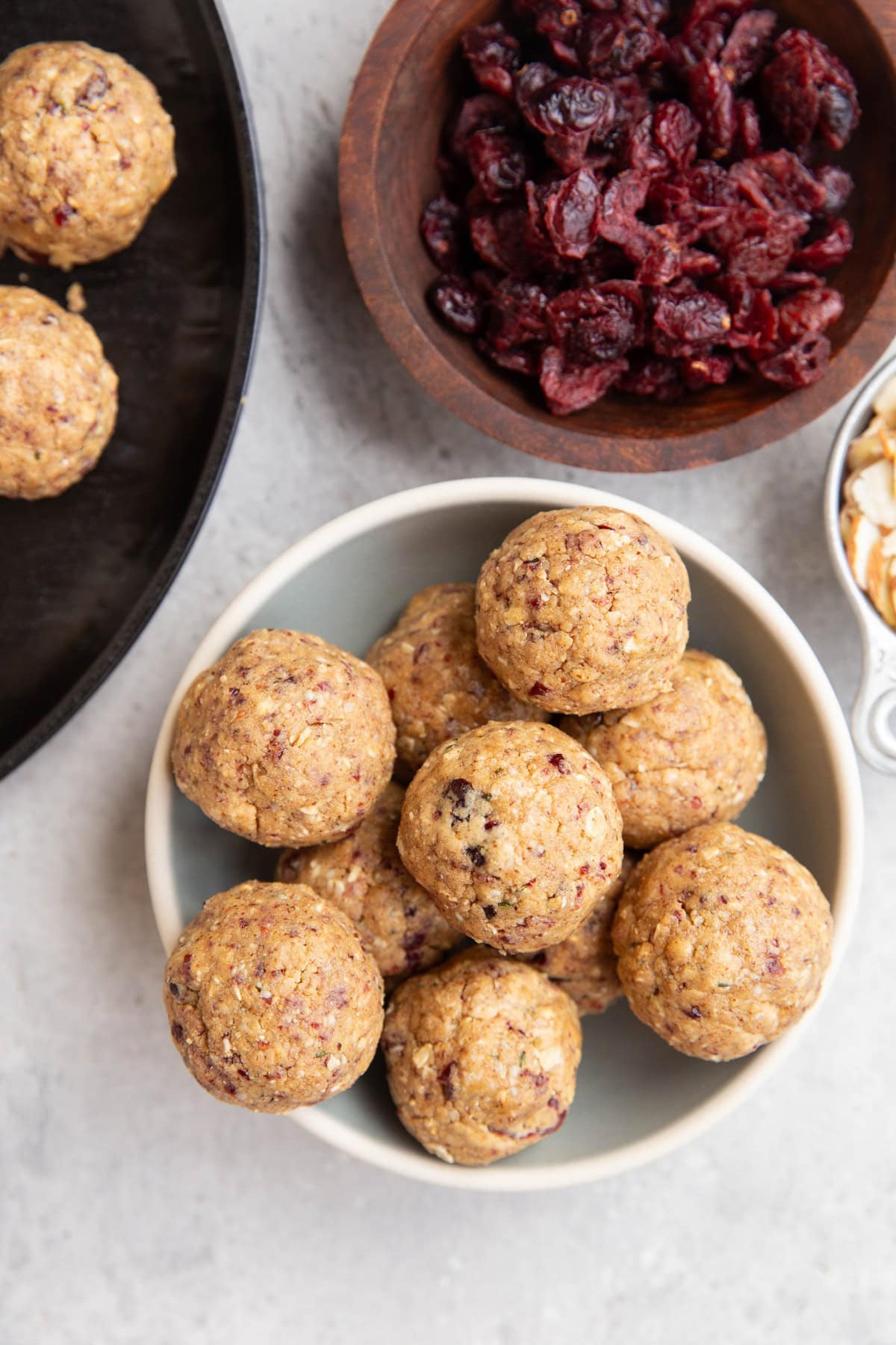 Bowl of protein bites with a bowl of dried cranberries to the side.