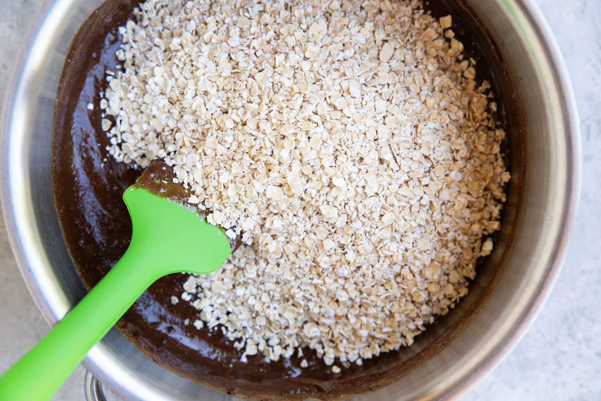 Oats on top of wet ingredients to make no bake cookie bars.